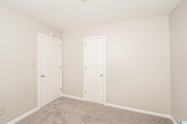 unfurnished room featuring light colored carpet and baseboards