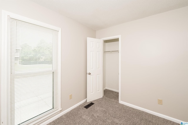 unfurnished bedroom featuring carpet flooring, baseboards, multiple windows, and a closet