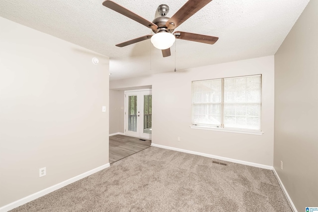 carpeted empty room with baseboards, a ceiling fan, a textured ceiling, and visible vents