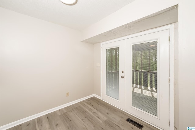 doorway with baseboards, visible vents, french doors, and light wood-style floors