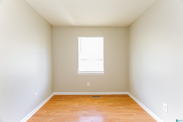 empty room with baseboards, light wood finished floors, and visible vents