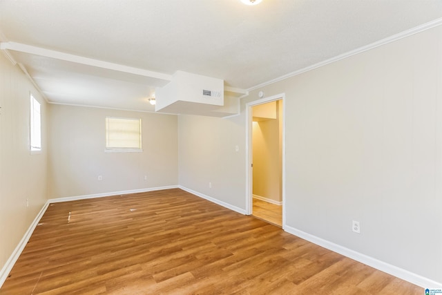 unfurnished room featuring light wood-type flooring, ornamental molding, baseboards, and visible vents