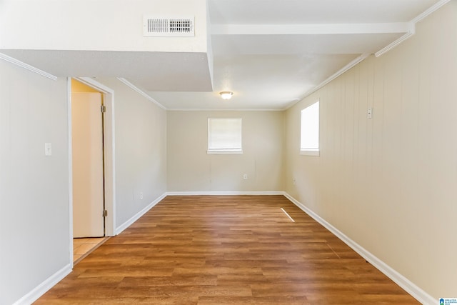 empty room featuring baseboards, visible vents, ornamental molding, and wood finished floors