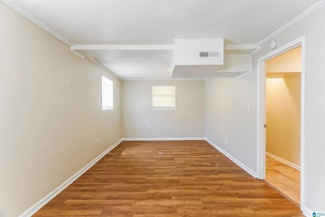 unfurnished room with visible vents, baseboards, crown molding, and wood finished floors