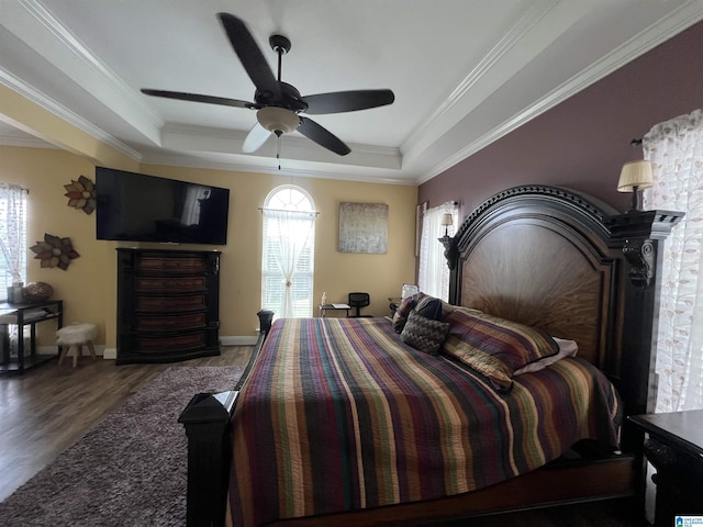bedroom featuring crown molding, a tray ceiling, multiple windows, and wood finished floors