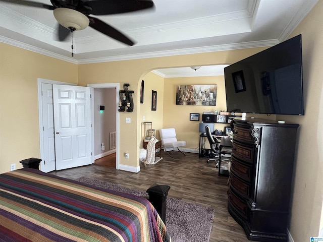 bedroom featuring crown molding, arched walkways, baseboards, dark wood-type flooring, and a tray ceiling