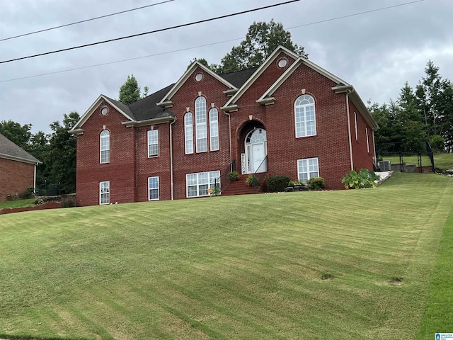 raised ranch with a front lawn and brick siding