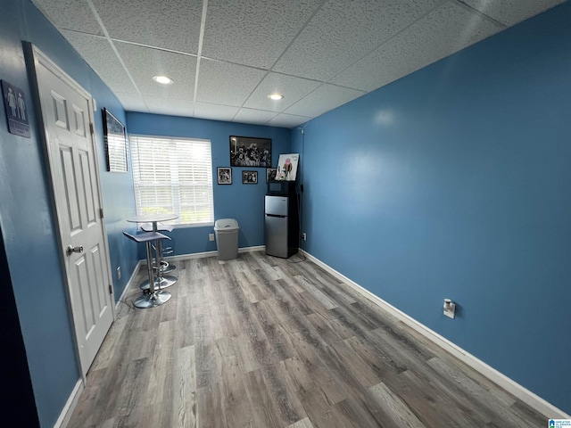interior space with baseboards, freestanding refrigerator, a paneled ceiling, and wood finished floors