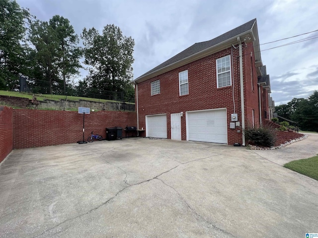 view of side of property featuring an attached garage, driveway, and brick siding
