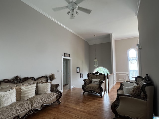 living area with crown molding, a ceiling fan, and wood finished floors