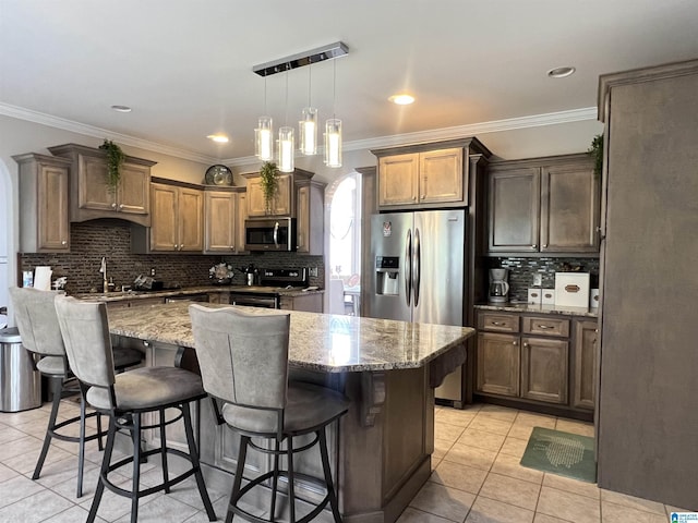 kitchen featuring crown molding, light tile patterned flooring, light stone countertops, appliances with stainless steel finishes, and tasteful backsplash