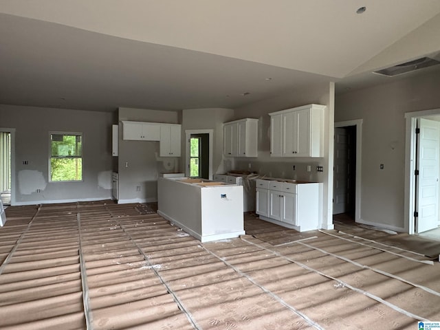 kitchen with white cabinets, baseboards, vaulted ceiling, and a center island