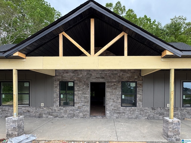view of front of home featuring board and batten siding, a patio area, and stone siding