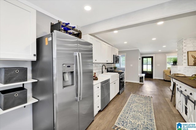 kitchen featuring appliances with stainless steel finishes, tasteful backsplash, wood finished floors, white cabinets, and recessed lighting