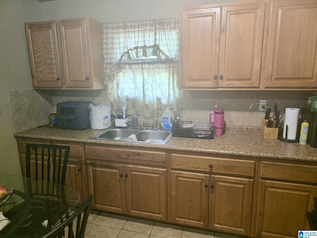 kitchen with backsplash, light tile patterned floors, a sink, and light countertops