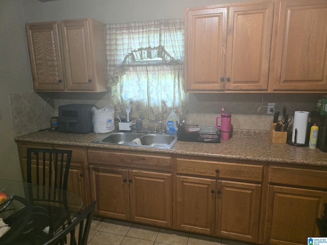 kitchen with backsplash, light tile patterned floors, a sink, and light countertops