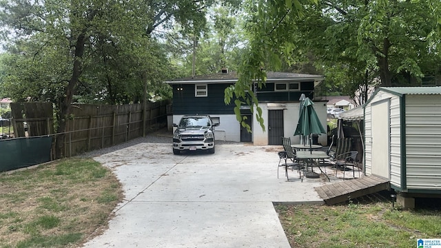 view of patio / terrace with fence, an outdoor structure, and a shed