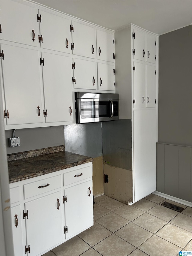 kitchen with white cabinets, stainless steel microwave, visible vents, and light tile patterned floors