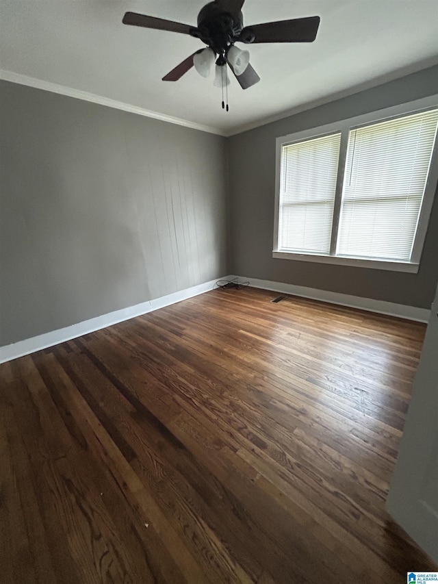 spare room featuring baseboards, ornamental molding, dark wood-style flooring, and a ceiling fan