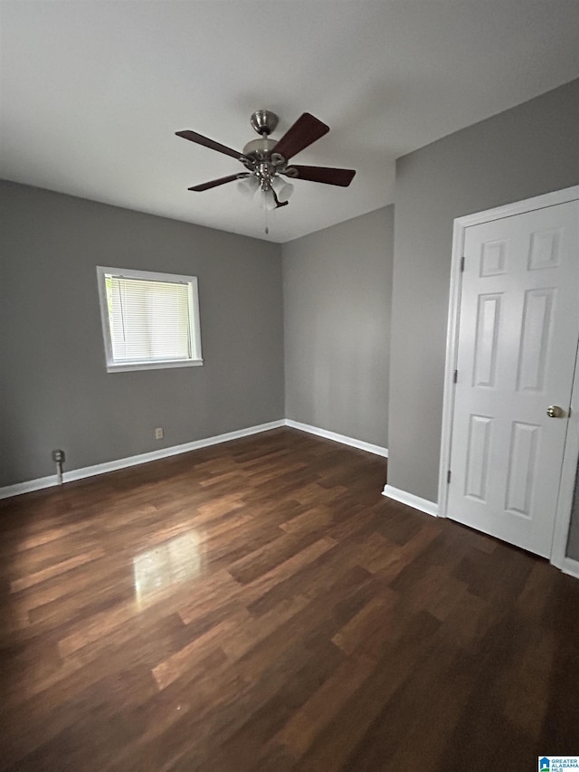 empty room with dark wood-style flooring, ceiling fan, and baseboards