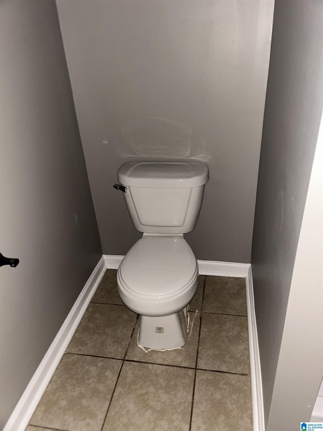 bathroom featuring baseboards, tile patterned floors, and toilet