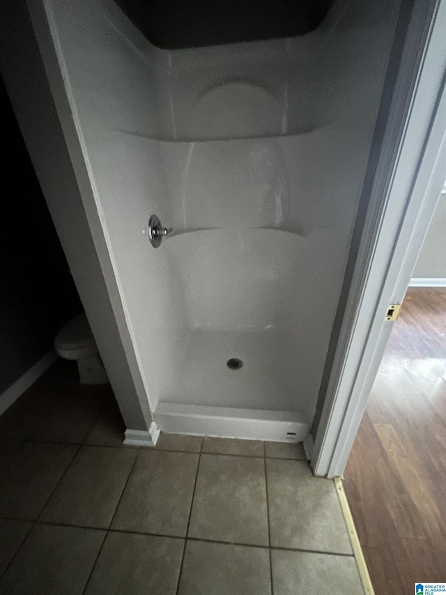 bathroom with baseboards, tile patterned flooring, walk in shower, and toilet