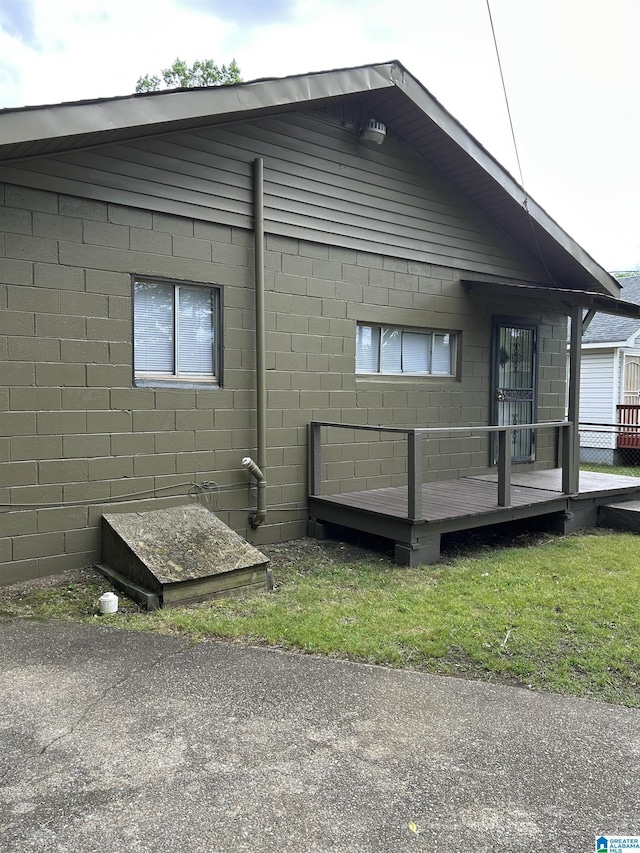 view of side of property featuring concrete block siding and a wooden deck