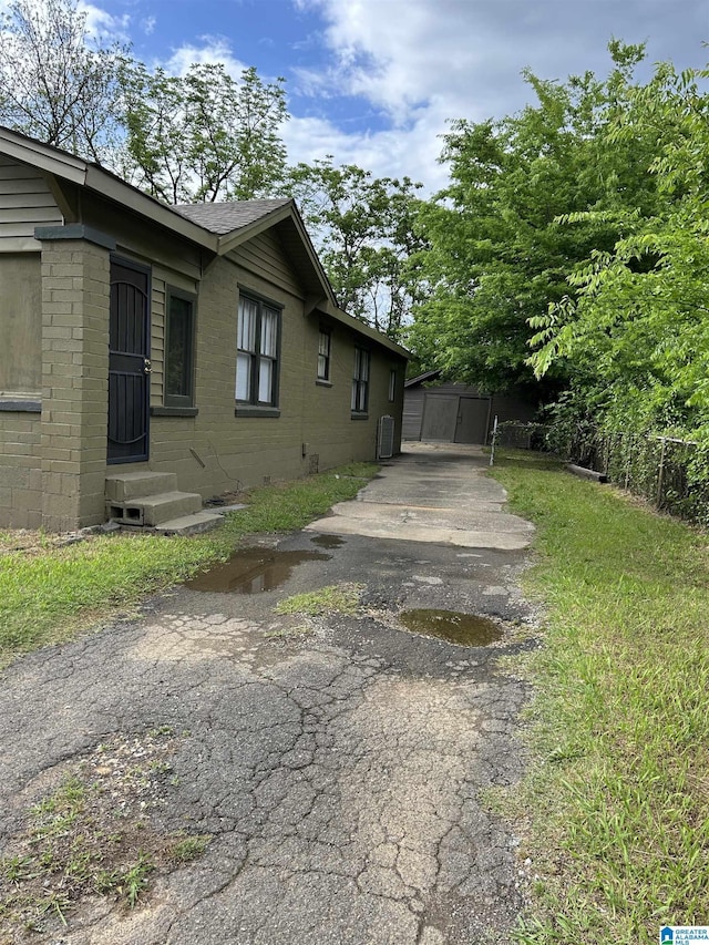 view of side of home with brick siding, driveway, and entry steps