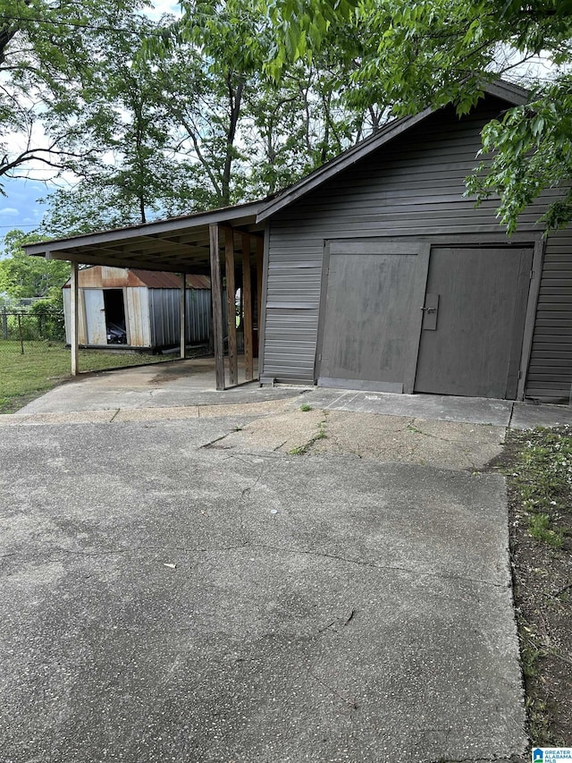 view of shed with an attached carport and driveway