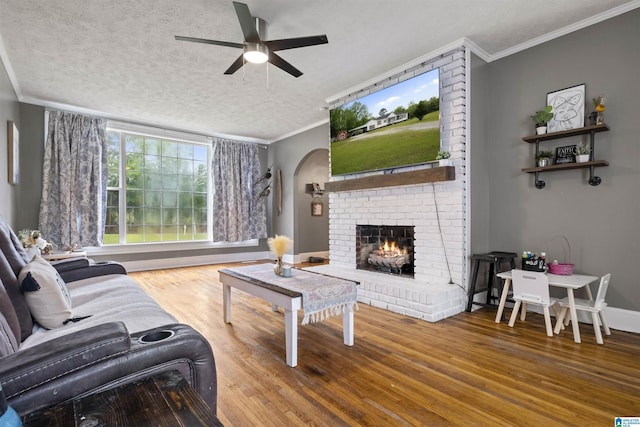 2857 Alexandria Wellington Rd, Alexandria, AL 36250 - living room with crown molding, a brick fireplace, wood finished floors, ceiling fan, and arched walkways
