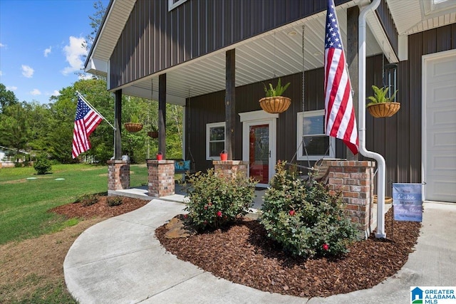 view of exterior entry with covered porch and a yard