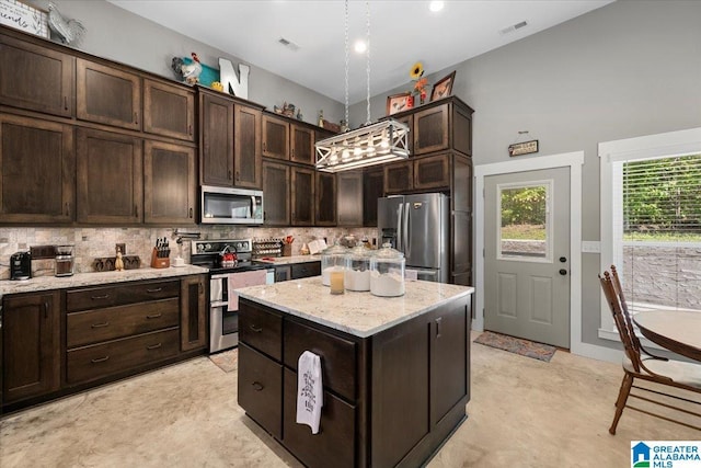 kitchen with appliances with stainless steel finishes, dark brown cabinetry, a center island, and visible vents