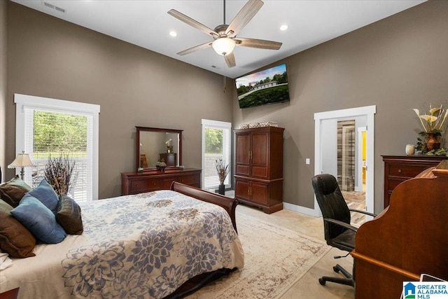 bedroom with visible vents, baseboards, a high ceiling, and multiple windows