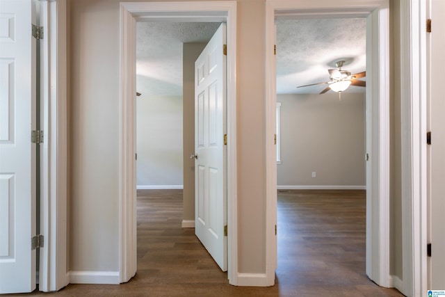 hall featuring baseboards, a textured ceiling, and wood finished floors