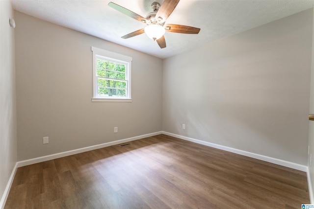 empty room featuring a ceiling fan, baseboards, visible vents, and wood finished floors