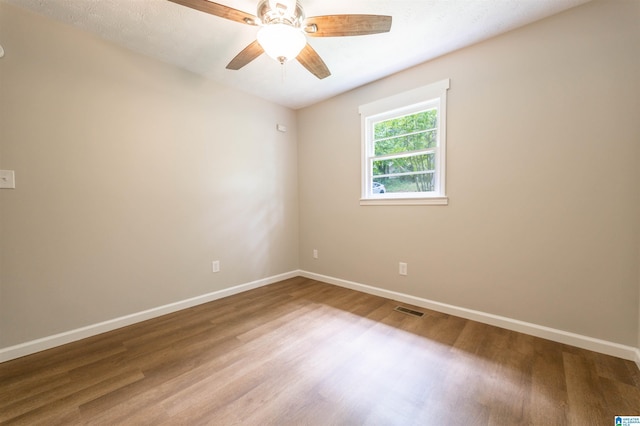spare room with visible vents, a ceiling fan, baseboards, and wood finished floors