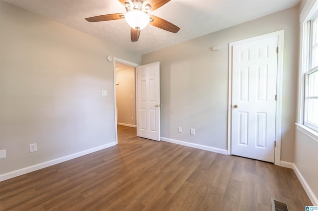 unfurnished bedroom with a ceiling fan, baseboards, visible vents, and wood finished floors