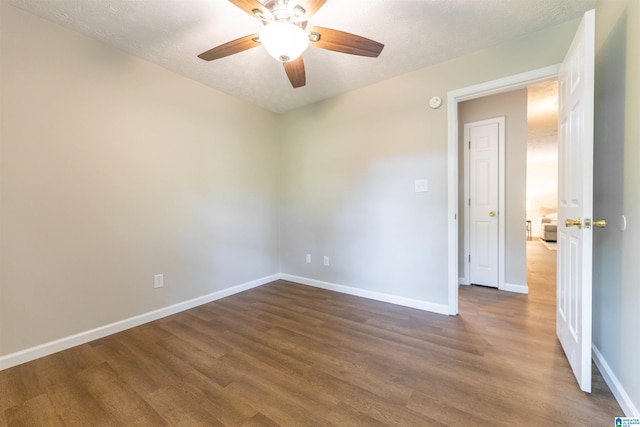 empty room with baseboards, a ceiling fan, and dark wood finished floors