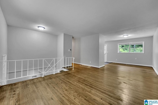 empty room featuring baseboards, wood finished floors, and visible vents