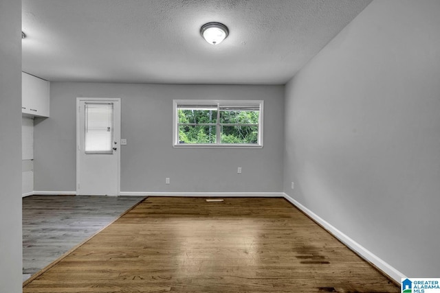 interior space featuring baseboards, a textured ceiling, and wood finished floors