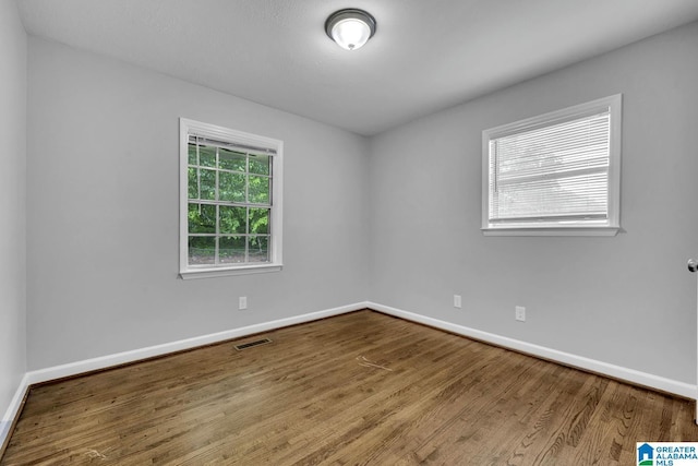 empty room with baseboards, wood finished floors, and visible vents