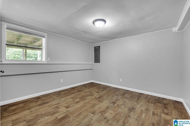 unfurnished room with baseboards, wood finished floors, and electric panel