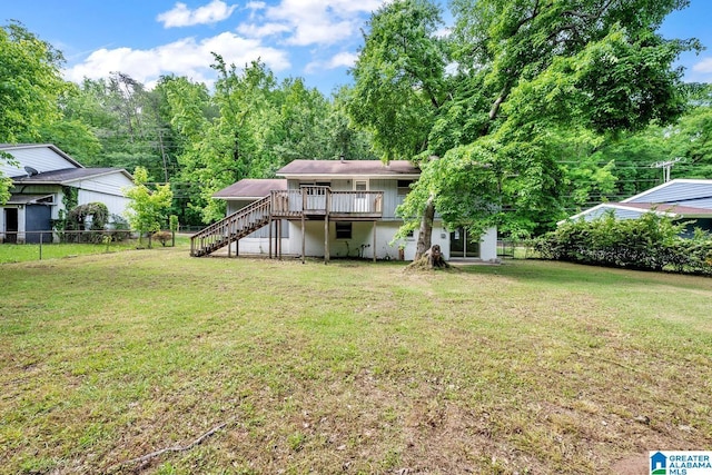 rear view of property featuring stairway, a deck, a yard, and fence