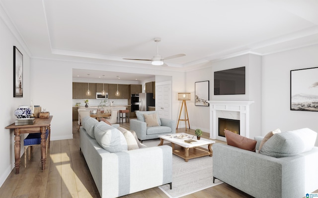 living room with a fireplace, baseboards, ceiling fan, a raised ceiling, and light wood finished floors