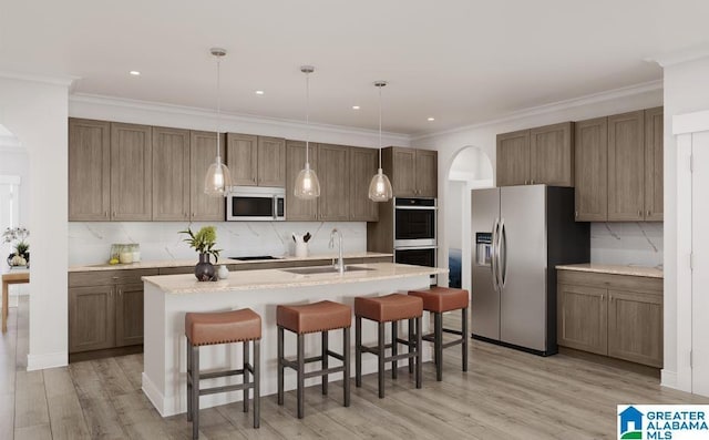kitchen featuring a sink, appliances with stainless steel finishes, decorative backsplash, and arched walkways