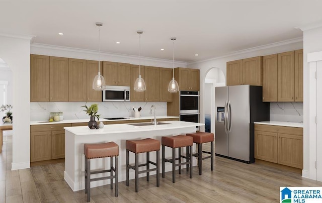 kitchen with a sink, arched walkways, tasteful backsplash, and stainless steel appliances