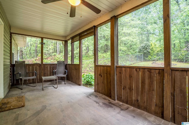 sunroom with a view of trees and ceiling fan