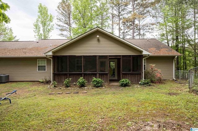 rear view of property featuring fence, a sunroom, a shingled roof, a lawn, and central air condition unit