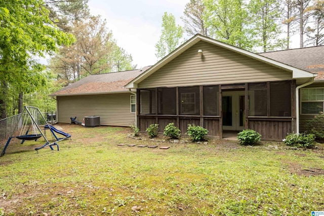 back of house featuring a yard, central AC unit, a shingled roof, and a sunroom