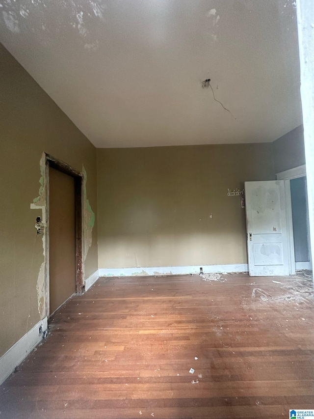 spare room with baseboards and wood finished floors